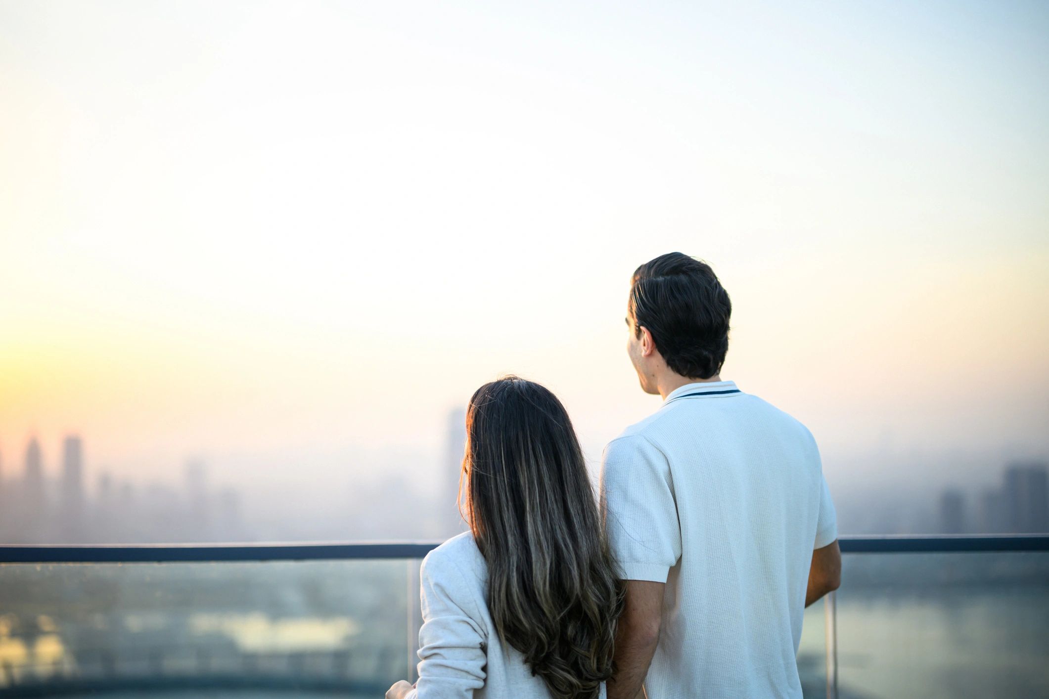 Couple on a rooftop terrace at sunset overlooking a skyline